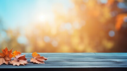 Naklejka na ściany i meble Empty wooden table with autumn leaves on bokeh sky background