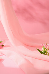 Pink background with gentle pink chiffon strips decorated with fresh flowers. Space in the middle...