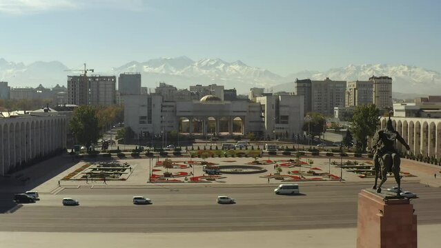 Magnificent view of Bishkek city center and snow-capped mountain peaks in the distance. Monument to Manas the Magnanimous. The building of the Office of the State Tax Service of Bishkek.