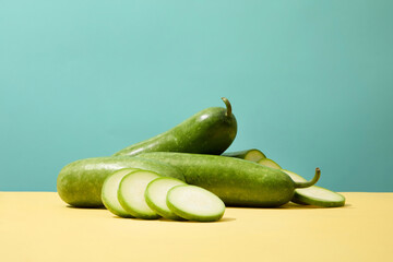 Fresh winter melon decorated on yellow surface and over blue background. Winter melon (Benincasa...