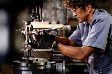 Asian worker in production plant drilling at machine. Professional worker near drilling machine on...
