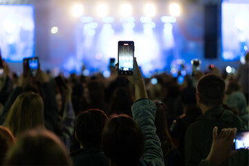 Silhouette of hands using camera phone to take pictures and videos at live concert, smartphone...