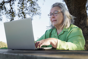 mature woman with white hair  smiling as she works at her computer