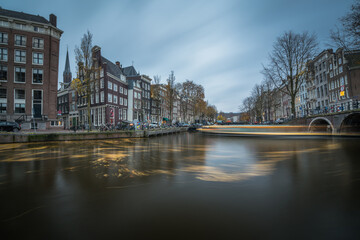 Long exposure canal with streaking boat and dark clouds in Amsterdam