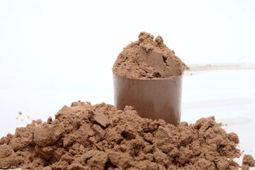Chocolate flavored protein milk powder, whey protein milk in measuring cups.  shake milk for muscle growth supplement.
