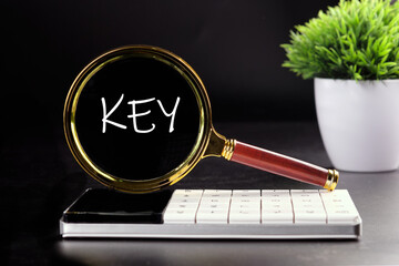 KEY text seen with a magnifying glass on a black background