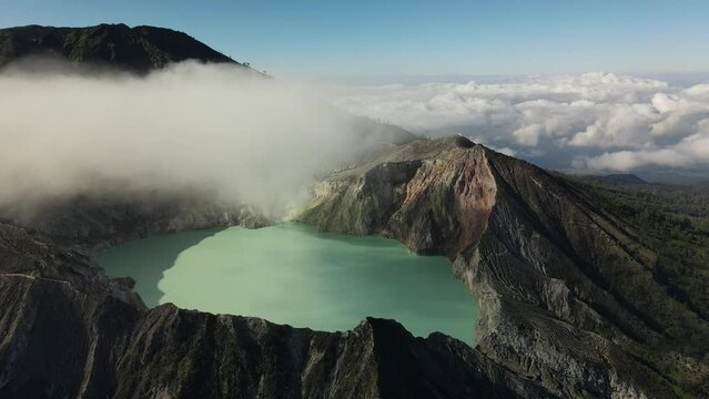 Drone flight on Ijen Volcano with sulfur clouds, acid lake, green mountain landscape