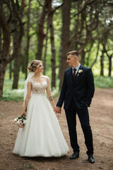 Naklejka premium the groom and the bride are walking in the forest