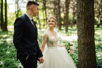 the groom and the bride are walking in the forest