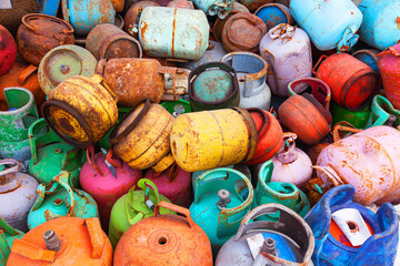 A pile of old used multi-colored gas cylinders of small size. Scrap metal from gas cylinders.