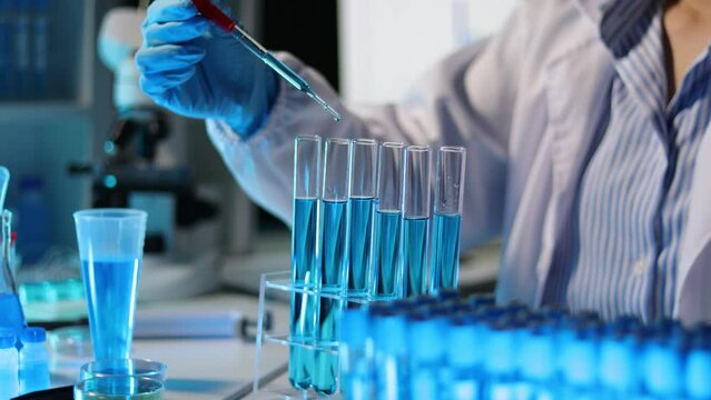 Doctor scientist analyzes a colored liquid to extract the DNA and molecules in the test tubes in the laboratory.