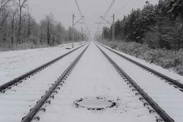 Railway and railroad tracks in the winter forest with snow and trees during winter. Beautiful landscape.