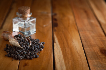 Dry organic Sheetal Chini (Piper cubeba) seeds, in a wooden scoop along with its essential oil.