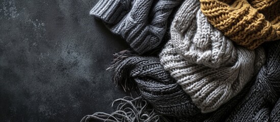 A stack of gray knitted winter sweaters on a dark background. Creative Banner. Copyspace image - obrazy, fototapety, plakaty