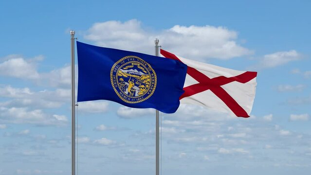 Alabama and Nebraska US state flags waving together on cloudy sky, endless seamless loop