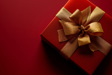 red christmas gift box with golden ribbon on red background with copyspace for wishes - 700527641
