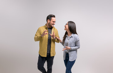 Ecstatic young partners laughing and discussing new project while standing against white background