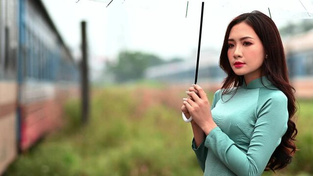 Young girl wearing a green color ao dai with a transparent umbrella the traditional costume of Vietnam