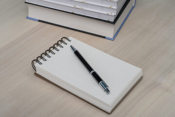 Notes z długopisem leży na biurku obok podręczników 