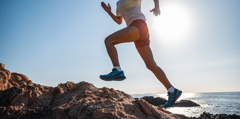 Woman runner running on sunrise seaside rocks