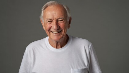  an older man wearing a white t - shirt with a pocket on his left chest and a smile on his right cheek, in front of a dark gray background.