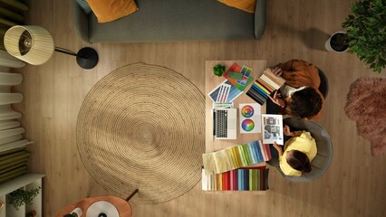 Top view of a man and a woman working from home. Young designers are discussing a project, comparing the textile color samples and inserting data into a laptop.