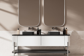 Beige hotel bathroom interior with double sink and mirrors, accessories