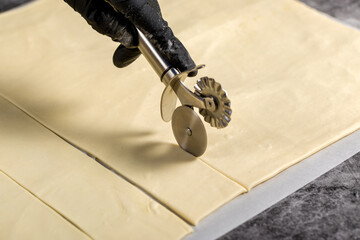 Process of cutting dough. The confectioner cuts the puff pastry with a roller knife