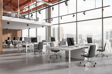 Modern coworking interior with desk and pc monitors in row, panoramic window