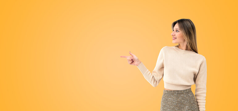 Happy young woman with finger pointing aside, copy space background