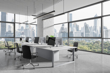 Office workplace interior with desk and pc monitors in row, panoramic window