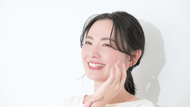 Busty, smiling, hand on cheeks, close-up, summarized hair, female beauty, white background, close-up slow-motion video.