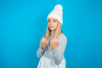 beautiful caucasian teen girl wearing grey sweater Ready to fight with fist defense gesture, angry and upset face, afraid of problem.