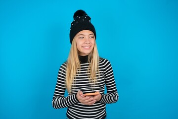 beautiful caucasian teen girl wearing striped sweater hold telephone hands read good youth news...