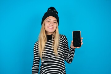 Smiling beautiful caucasian teen girl wearing striped sweater Mock up copy space. Hold mobile phone...