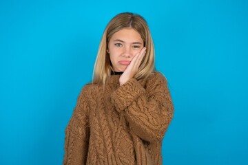 Sad lonely beautiful teen girl touches cheek with hand bites lower lip and gazes with displeasure....