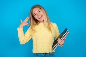 beautiful caucasian teen girl wearing yellow sweater foolishness around shoots in temple with fingers makes suicide gesture. Funny model makes finger gun pistol