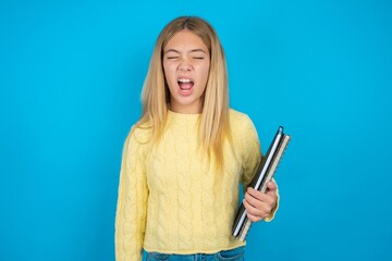 beautiful caucasian teen girl wearing yellow sweater yawns with opened mouth stands. Daily morning...