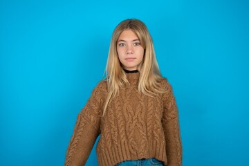 Stunned beautiful caucasian teen girl wearing brown sweater stares reacts on shocking news....