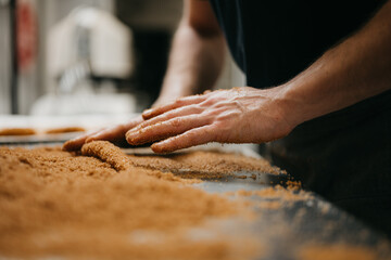Baker kneading dough on table topped of with cinnamon sugar