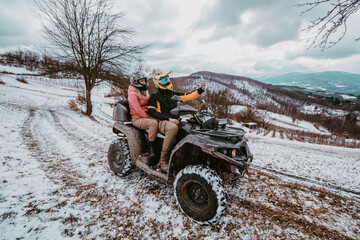  A couple enjoys an adventurous quad ride through the snowy landscape, capturing the thrill of the...