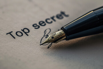 Fototapeta premium Close-up of an ink pen with a nib on a white sheet of paper With top secret inscription