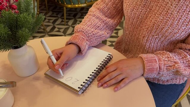 New Year goals 2025. Womans hand writing in notebook goals list. Concept of new year planning.