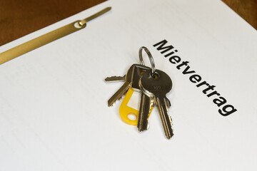 Schlüssel und deutscher Mietvertrag für eine neue Wohnung liegen auf einem Tisch