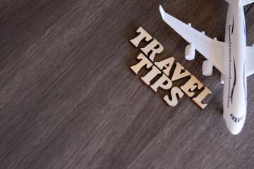 Toy plane and word TRAVEL TIPS on wooden table with copy space for text.