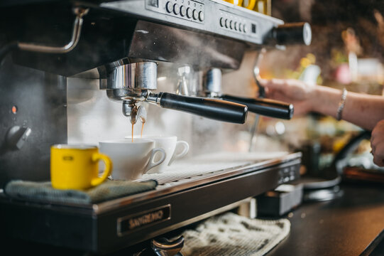 Two espresso's being made with coffee maker machine in a restaurant.