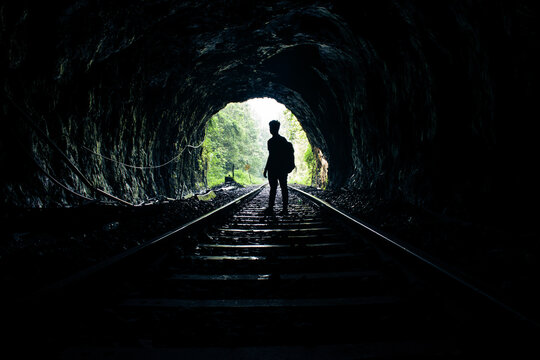 Fototapeta Silhouette of a man standing in a tunnel of rails.