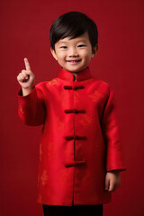 Asian cute boy wearing traditional cheongsam qipao dress with gesture of congratulation isolated on red background. Happy Chinese new year.