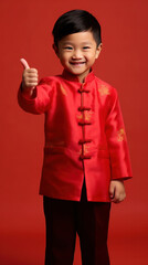 Asian cute boy wearing traditional cheongsam qipao dress with gesture of congratulation isolated on red background. Happy Chinese new year.