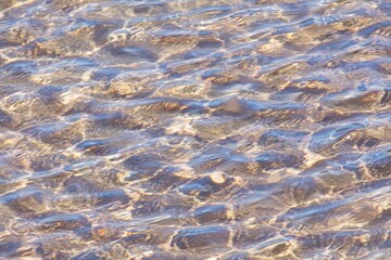 Sand sea bottom and small waves in sunny spring weather.